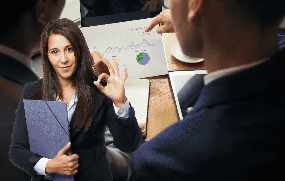 Ejecutiva apuntando a un gráfico en traje formal.