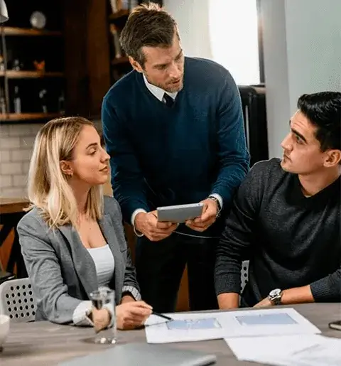 Tres ejecutivos reunidos alrededor de una mesa con una laptop.